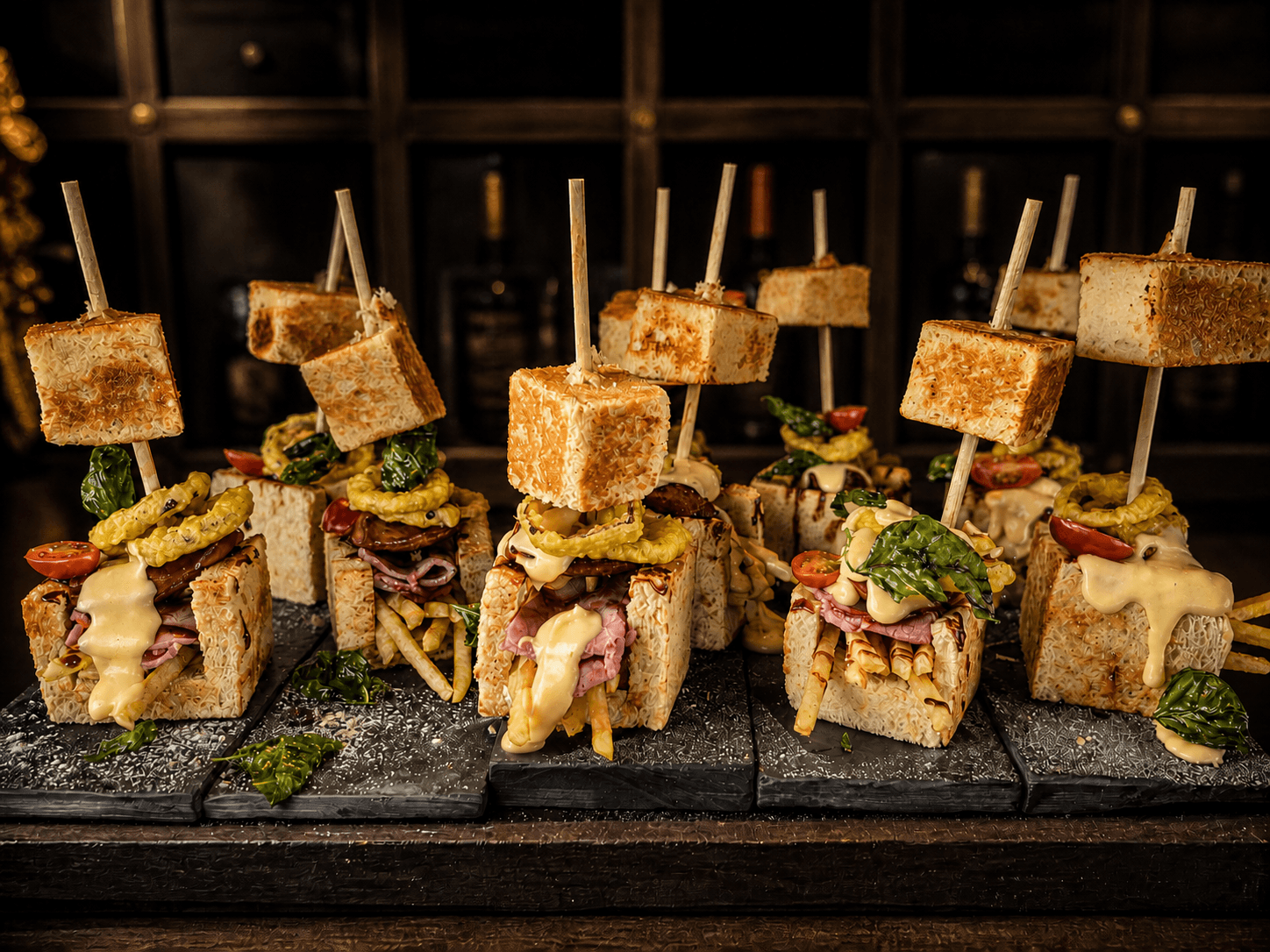 A line of open-faced canapés skewered with roast beef, pickled onion, and cheese.