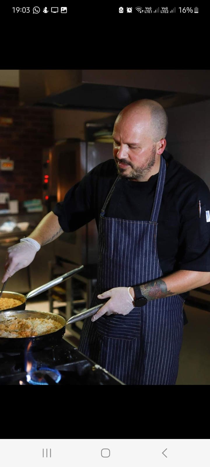 Chef Tristan cooking at the pass, plating a dish over an open flame.